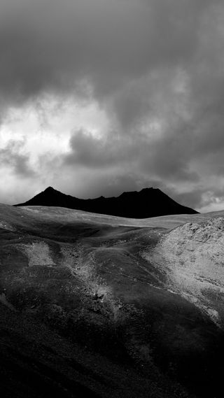Photo en noir et blanc : une montagne noire, un ciel menaçant